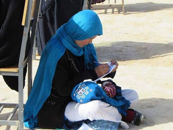 afghan woman writes exam while nursing her baby afghan woman writes exam while nursing her baby
