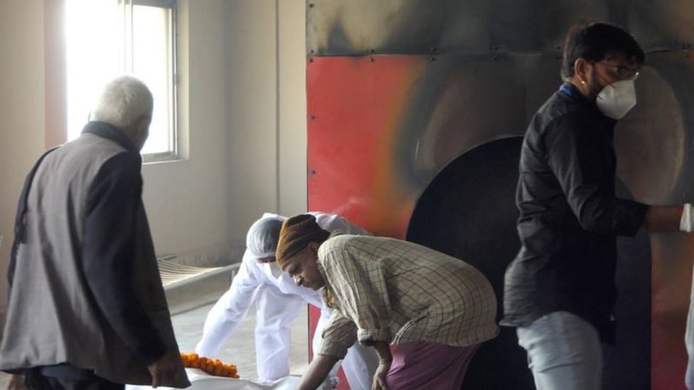 பாதுகாப்பு உடையின்றி உடல்களை எரிக்கும் ஊழியர்கள்